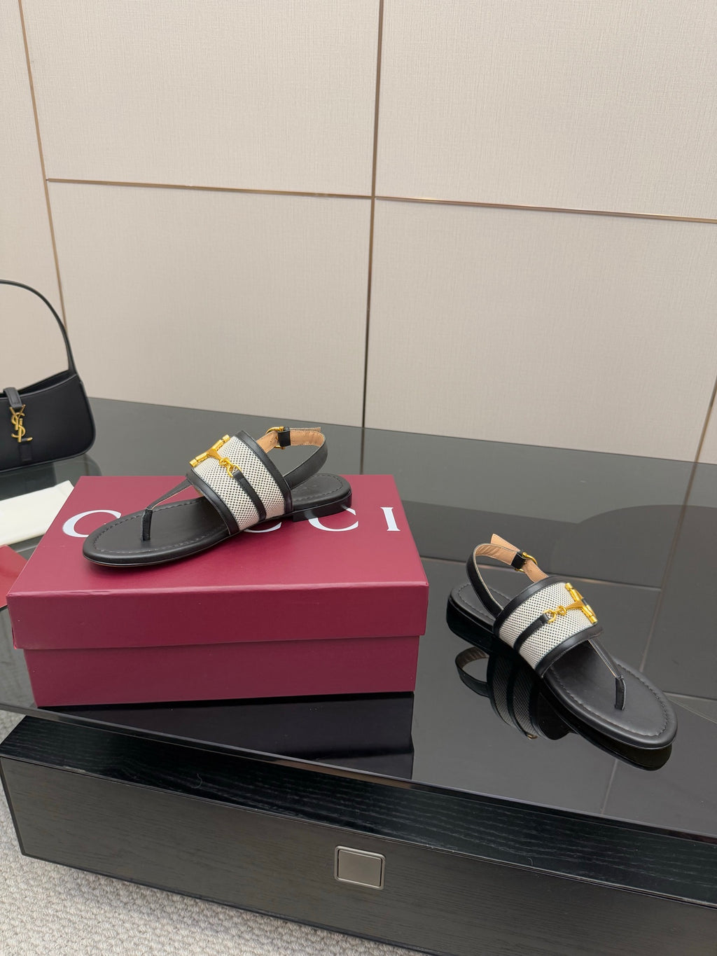 Ladies slide sandals, side view: black leather thong with white check strap and gold buckle
