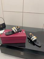 Ladies slide sandals, side view: black leather thong with white check strap and gold buckle