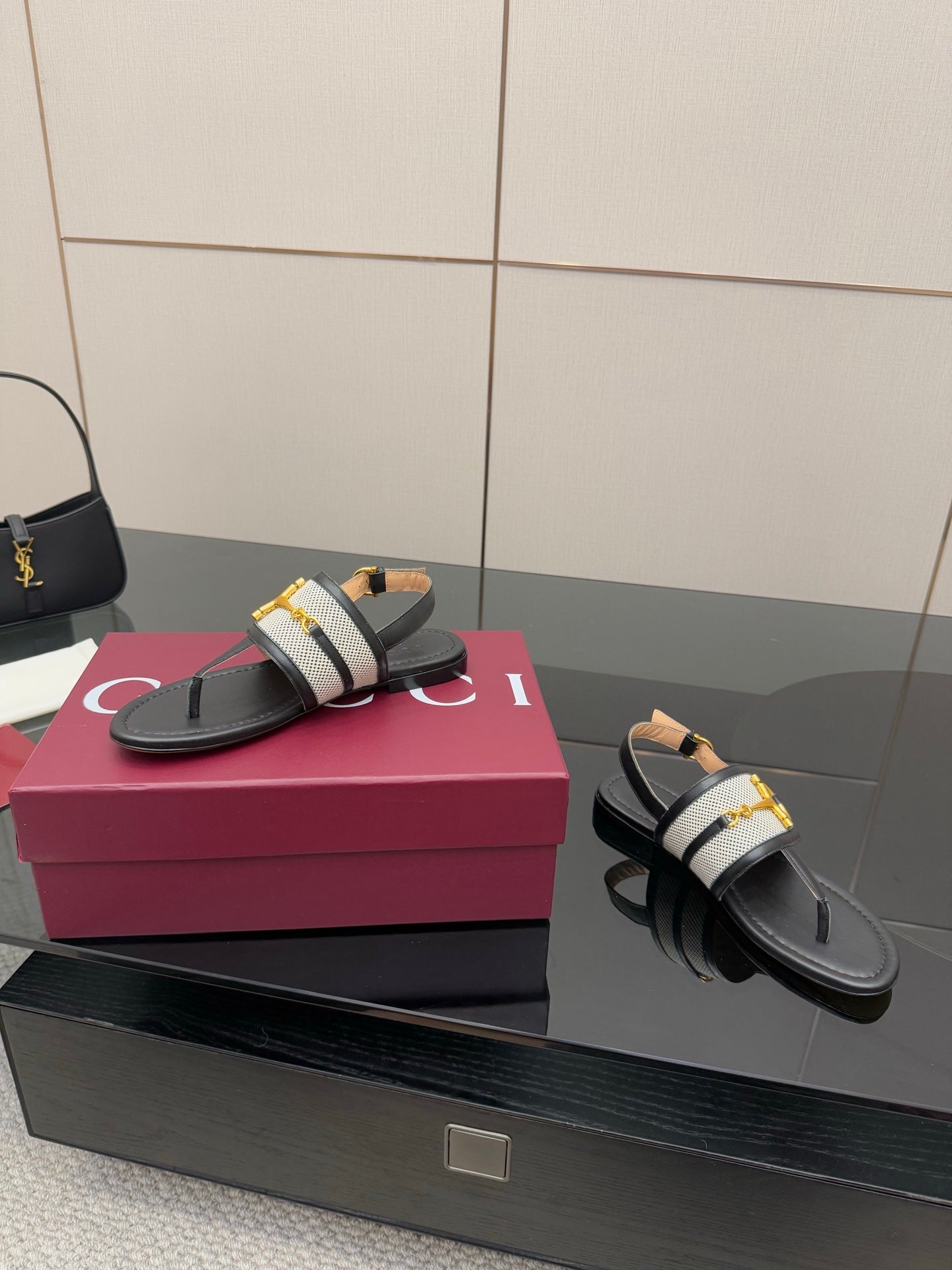 Ladies slide sandals, side view: black leather thong with white check strap and gold buckle