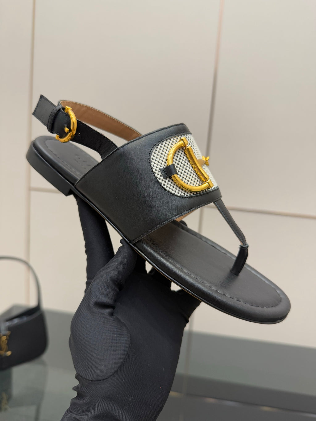 Ladies slide sandal on hand: black leather slide with white check band and gold buckle