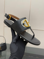 Ladies slide sandal on hand: black leather slide with white check band and gold buckle