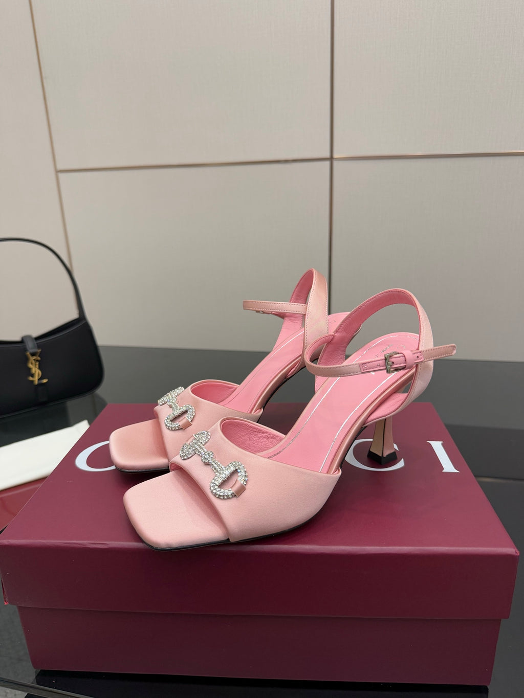 Pink heeled sandals with open toe, ankle strap, and jeweled buckle detail