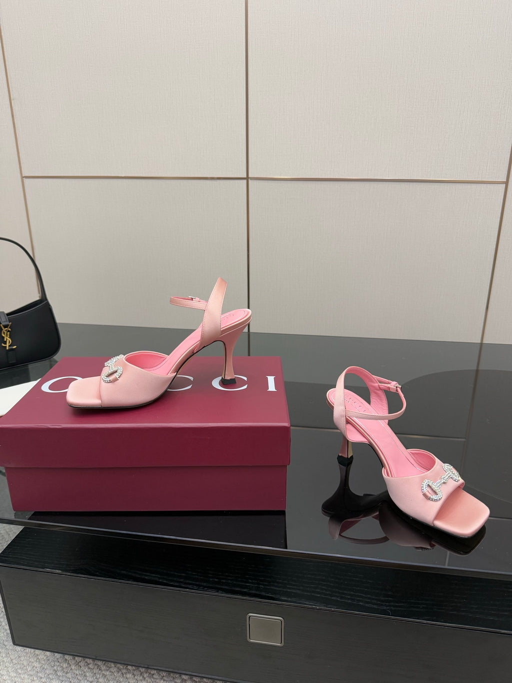 Pink open-toe heeled sandals with slim ankle strap and jeweled emblem