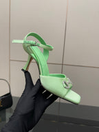 Mint green slingback heeled sandal with rhinestone buckle and stiletto heel, held