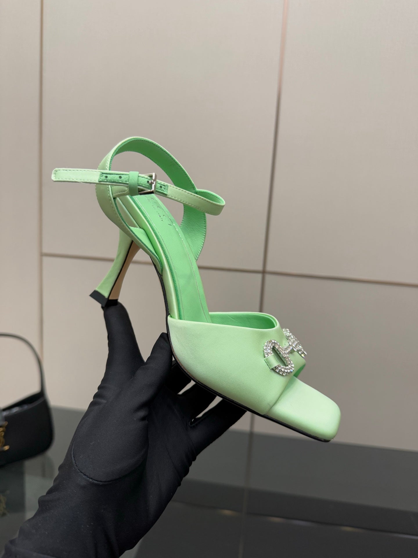 Mint green slingback heeled sandal with rhinestone buckle and stiletto heel, held