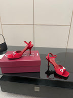 Pair of red Gucci heeled sandals on retail box, with open toe and ankle strap