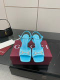 Light blue ladies heeled sandals with jeweled cross-buckle detail, open toe.