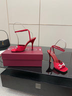 Red open-toe heeled sandals with silver buckle detail and high slim heel, on box