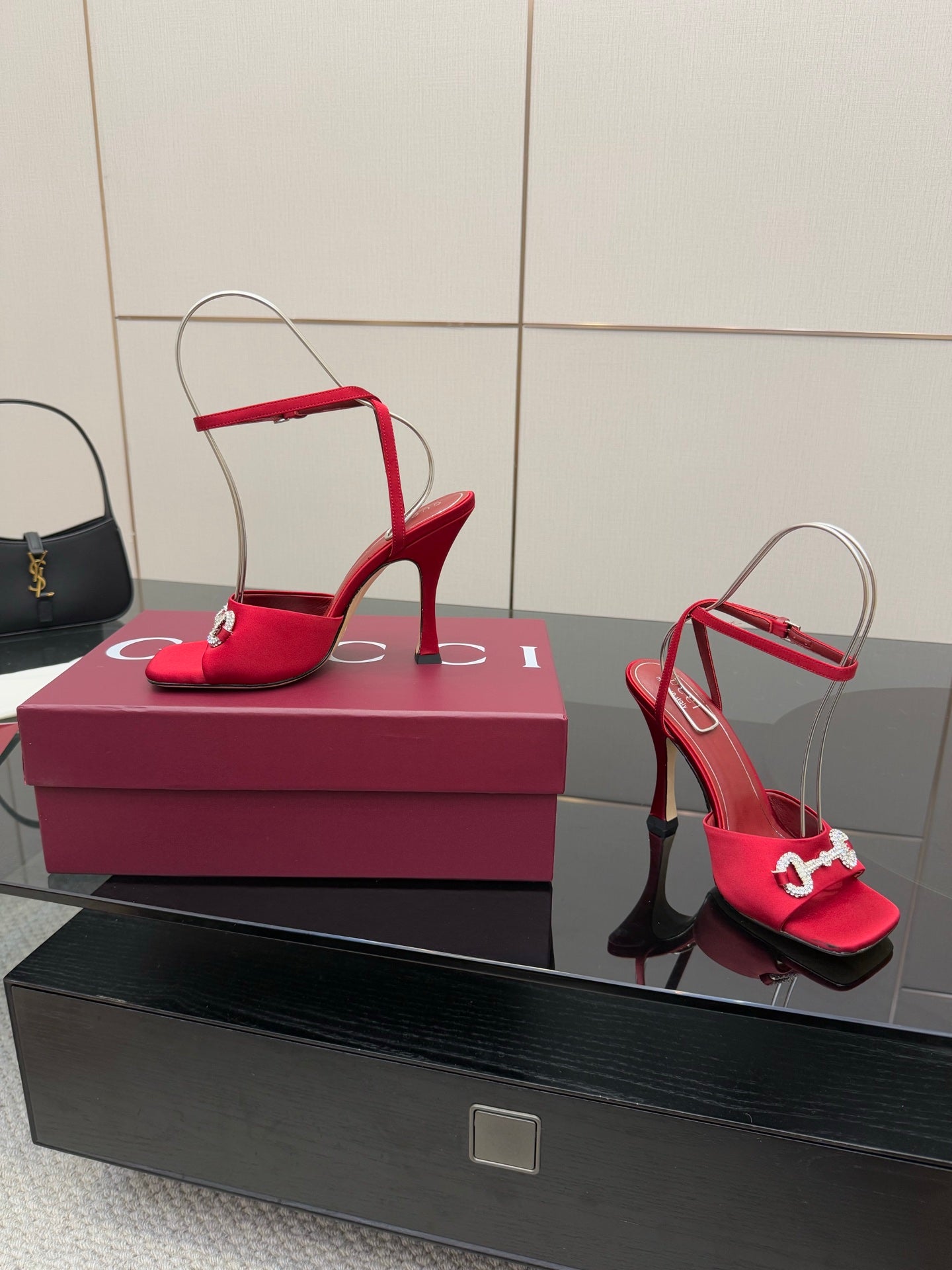 Red open-toe heeled sandals with silver buckle detail and high slim heel, on box