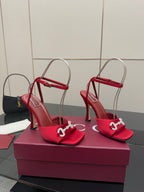 Red open-toe heeled sandals with thin straps and silver buckle detail, side view
