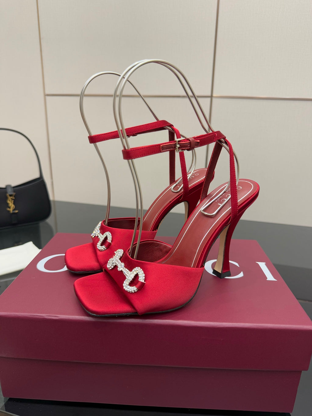Red heeled sandals with decorative silver buckle on the toe strap, front view