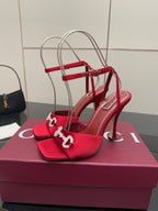 Red heeled sandals with decorative silver buckle on the toe strap, front view