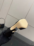 Gucci ladies black heeled sandal sole with beige outsole, held in gloved hand