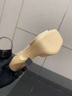 Cream sandal sole and heel view, stitched edge detail, on gloved hand