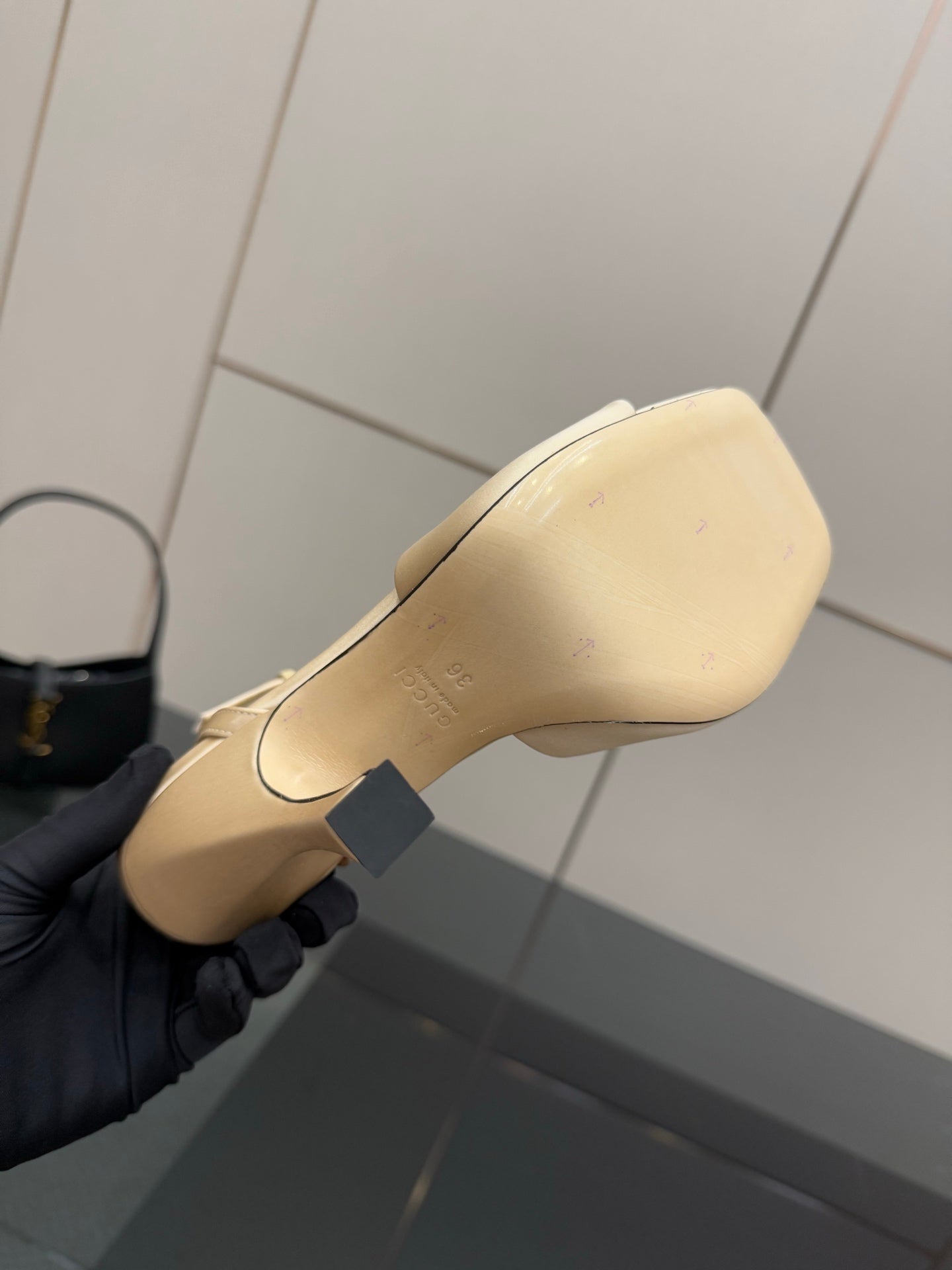 Cream sandal sole and heel view, stitched edge detail, on gloved hand