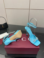 Women’s sky-blue heeled sandals with open toe, ankle strap, and gold-tone hardware