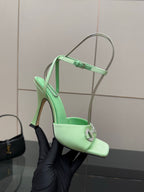 Green open-toe heeled sandal held by gloved hand, slingback strap and buckle