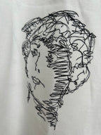 Off-white T-shirt close-up of black line-drawing face graphic