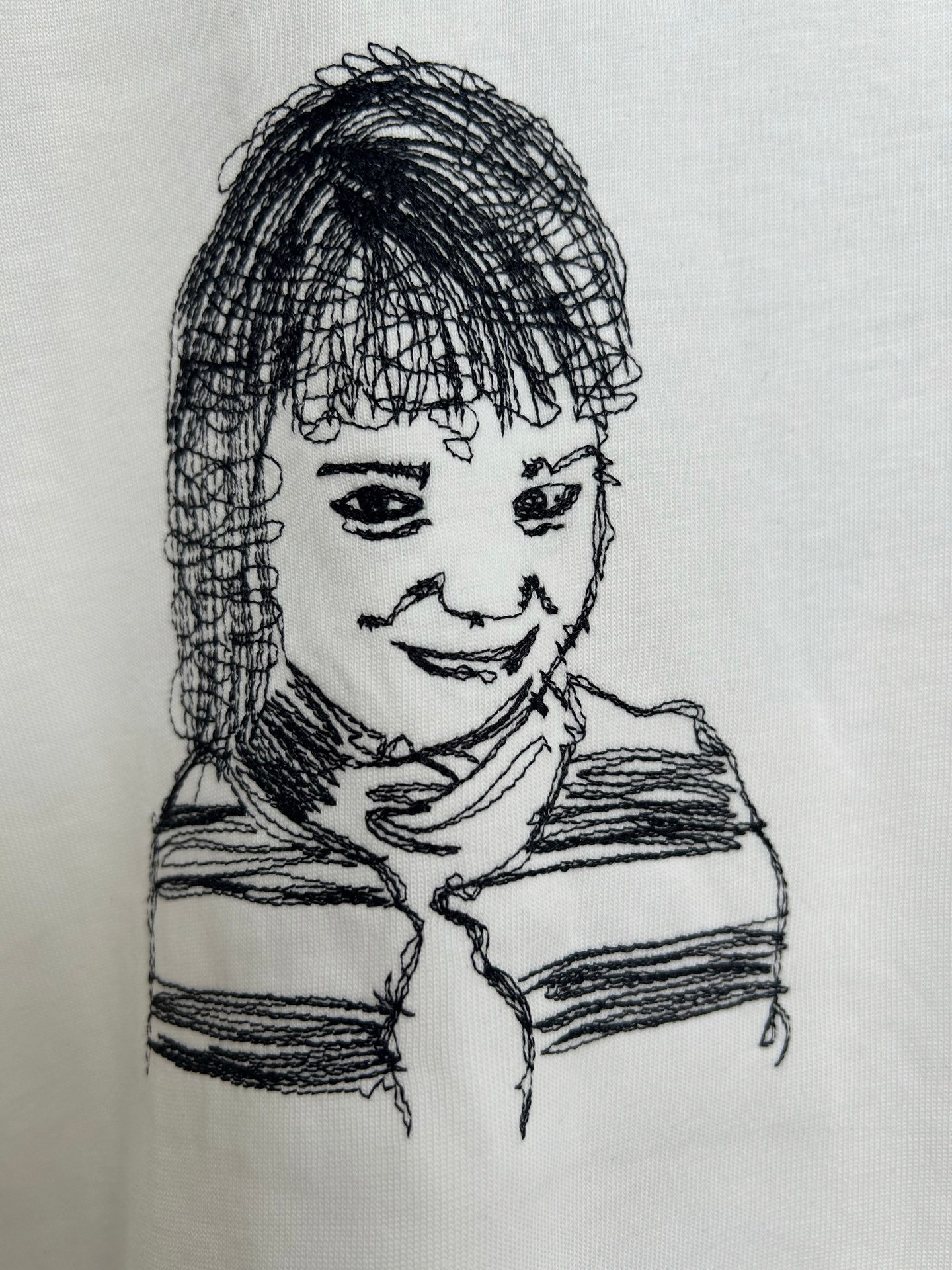 Off-white T-shirt close-up of black line-drawing portrait graphic