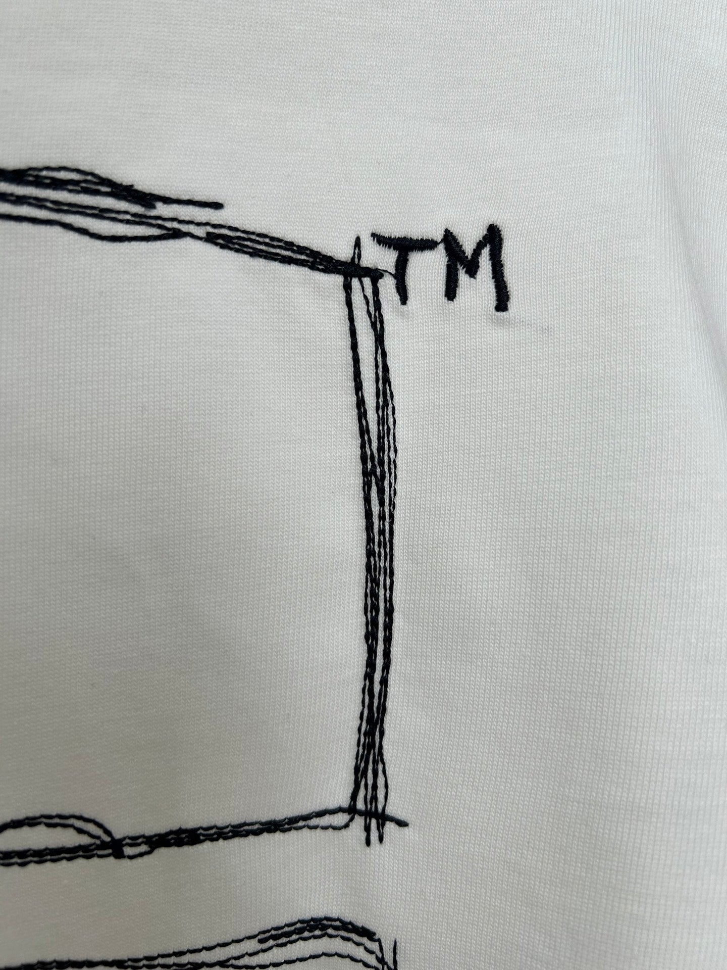 Off-white T-shirt back graphic detail with small “TM” text near top