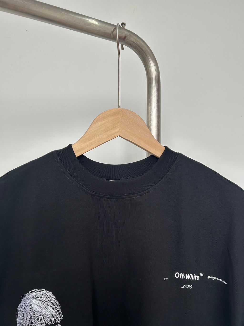 Black T-shirt close-up with small chest logo and white printed details