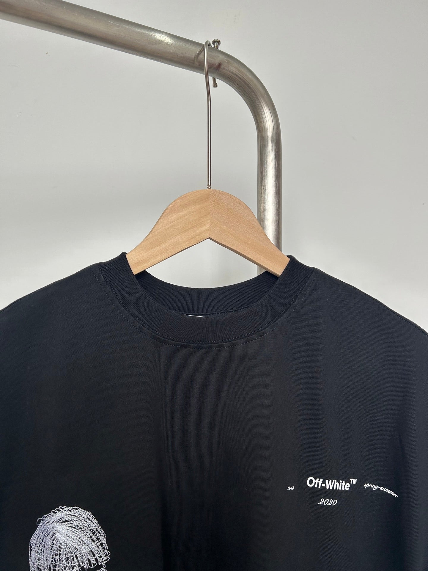 Black T-shirt close-up with small chest logo and white printed details
