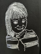 Black T-shirt with large white embroidered-style face graphic on front