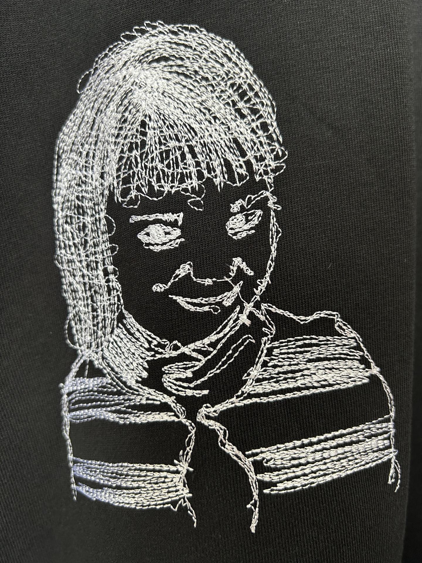 Black T-shirt with large white embroidered-style face graphic on front