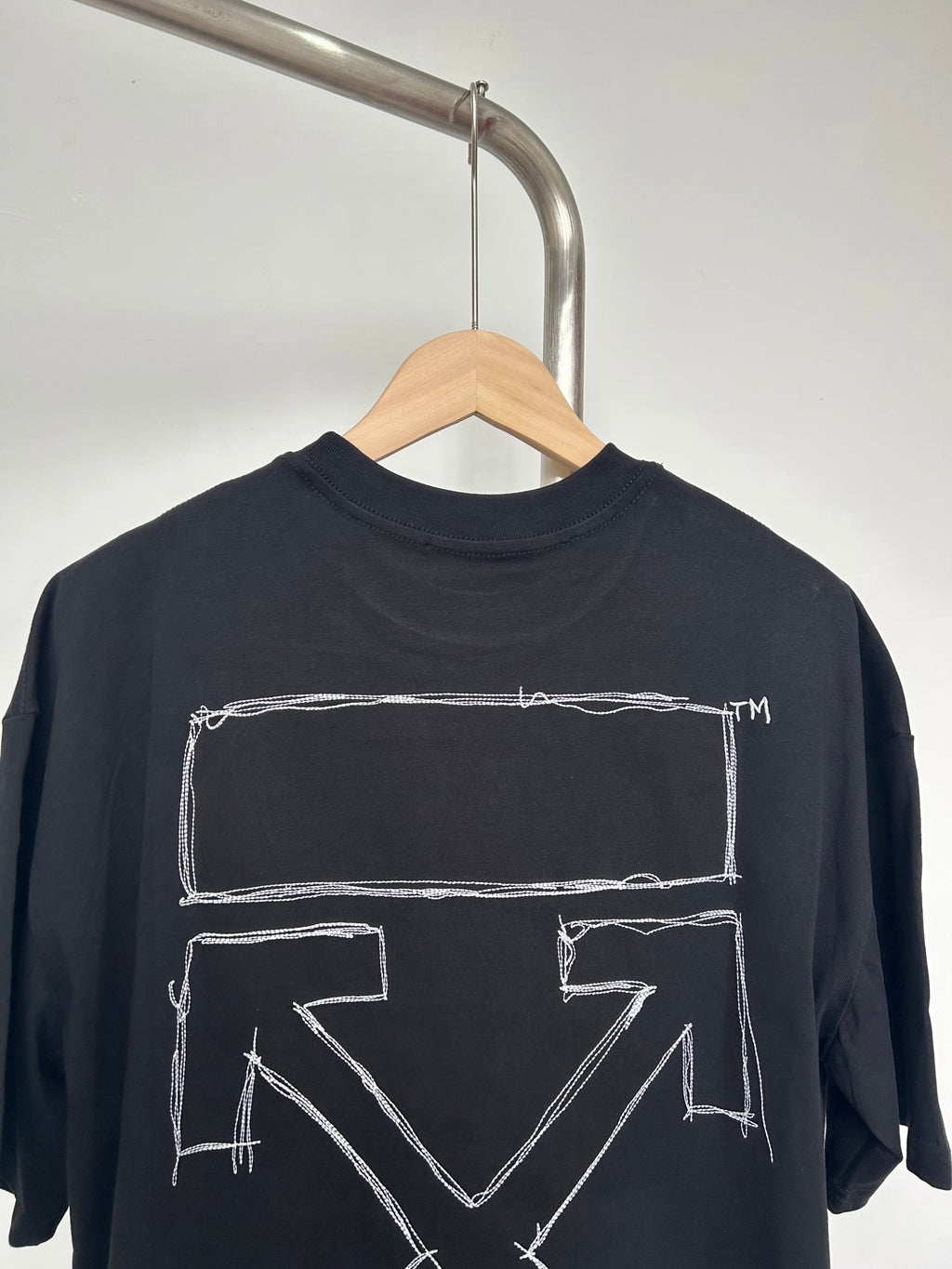 Black T-shirt back with large white rectangular arrow graphic and small logo