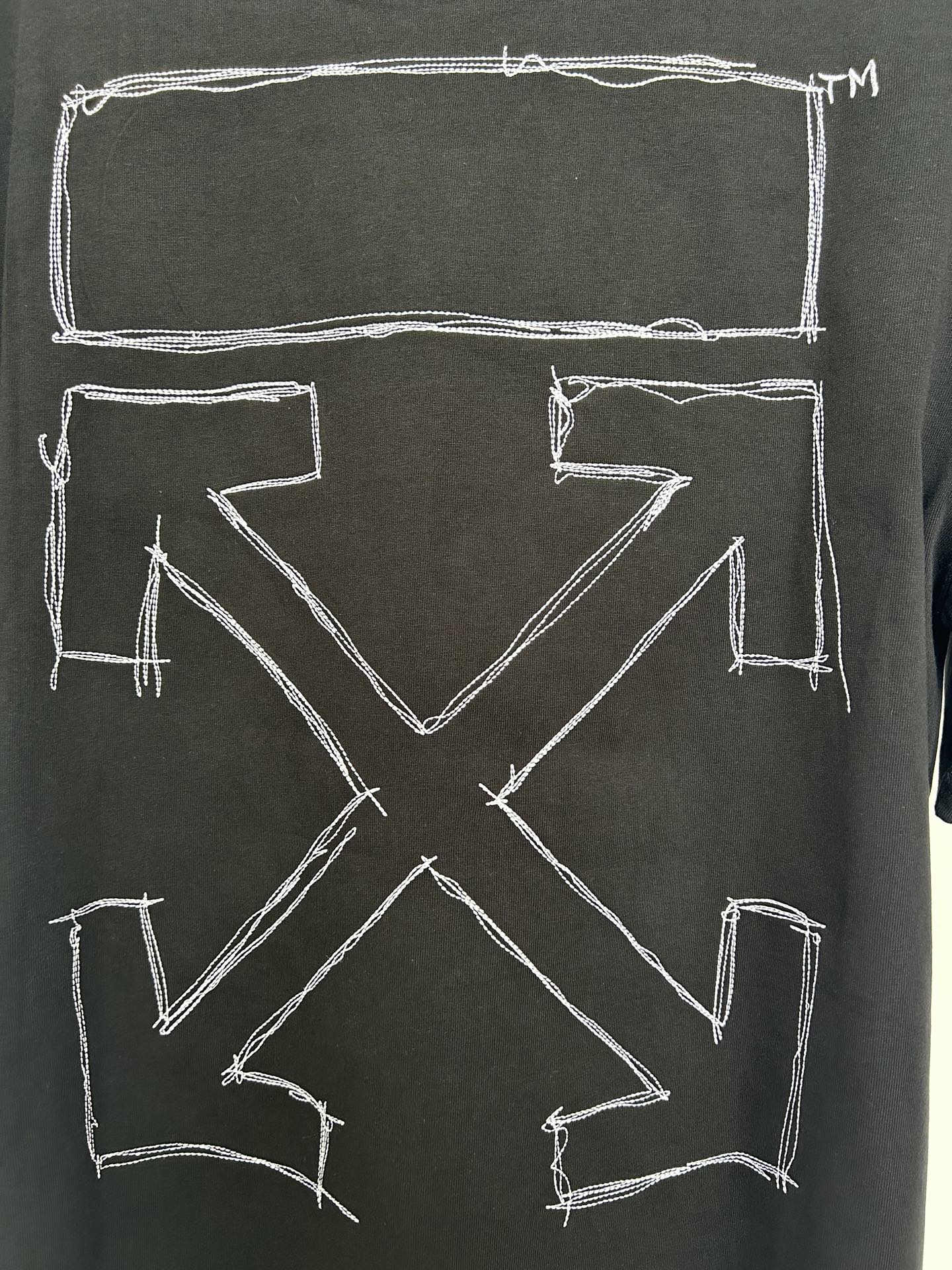 Black T-shirt back close-up with large X-shaped arrow outline graphic