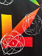 Black T-shirt closeup of colorful pinwheel and orbit graphic with white lines