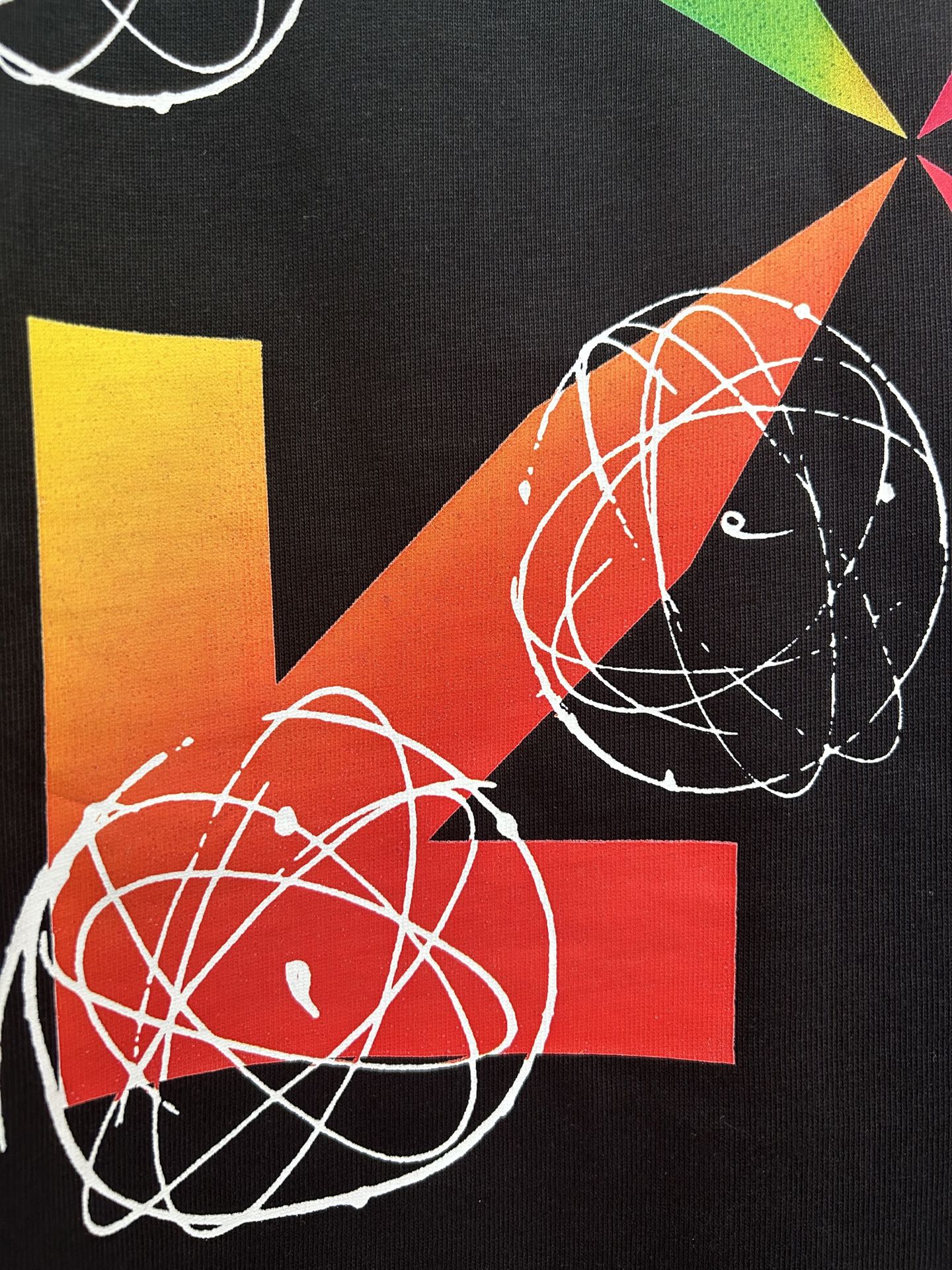 Black T-shirt closeup of colorful pinwheel and orbit graphic with white lines