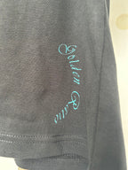 Dark T-shirt sleeve with teal script logo and visible stitched hem