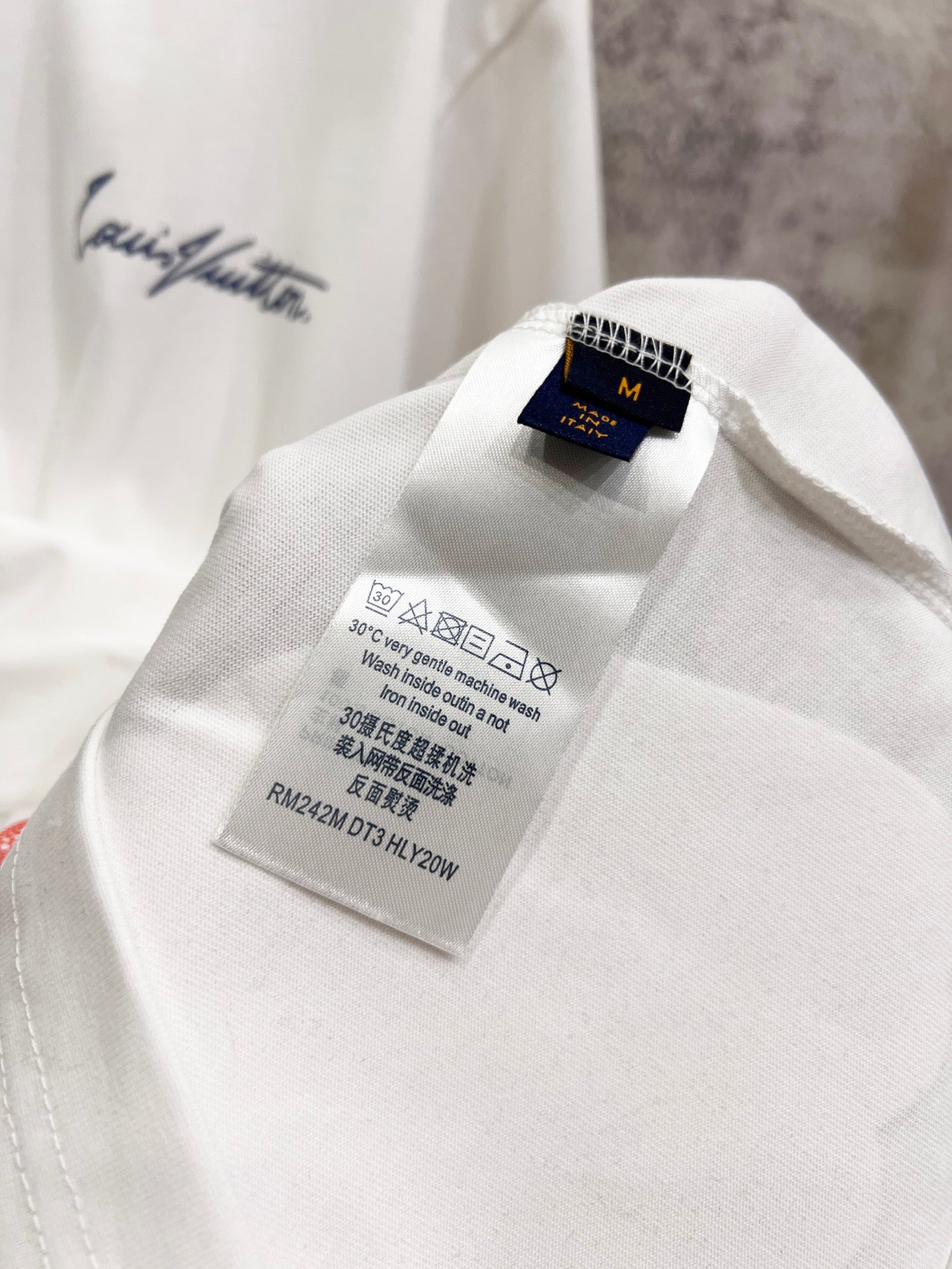 White T-shirt inner care label and Louis Vuitton brand tag inside collar