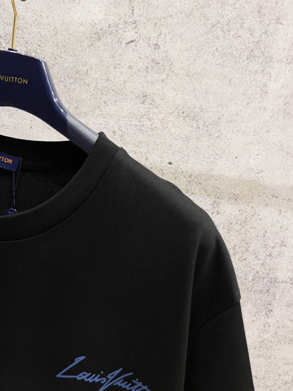 Black Louis Vuitton T-shirt with blue logo on the chest, close-up