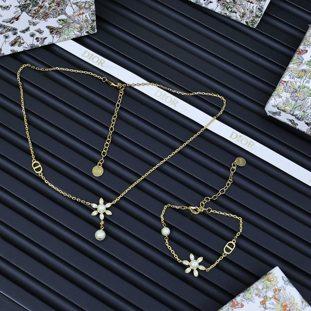 Gold-tone charm jewelry set with floral and pearl pendants, multiple linked chains.