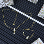 Gold-tone charm jewelry set with floral and pearl pendants, multiple linked chains.