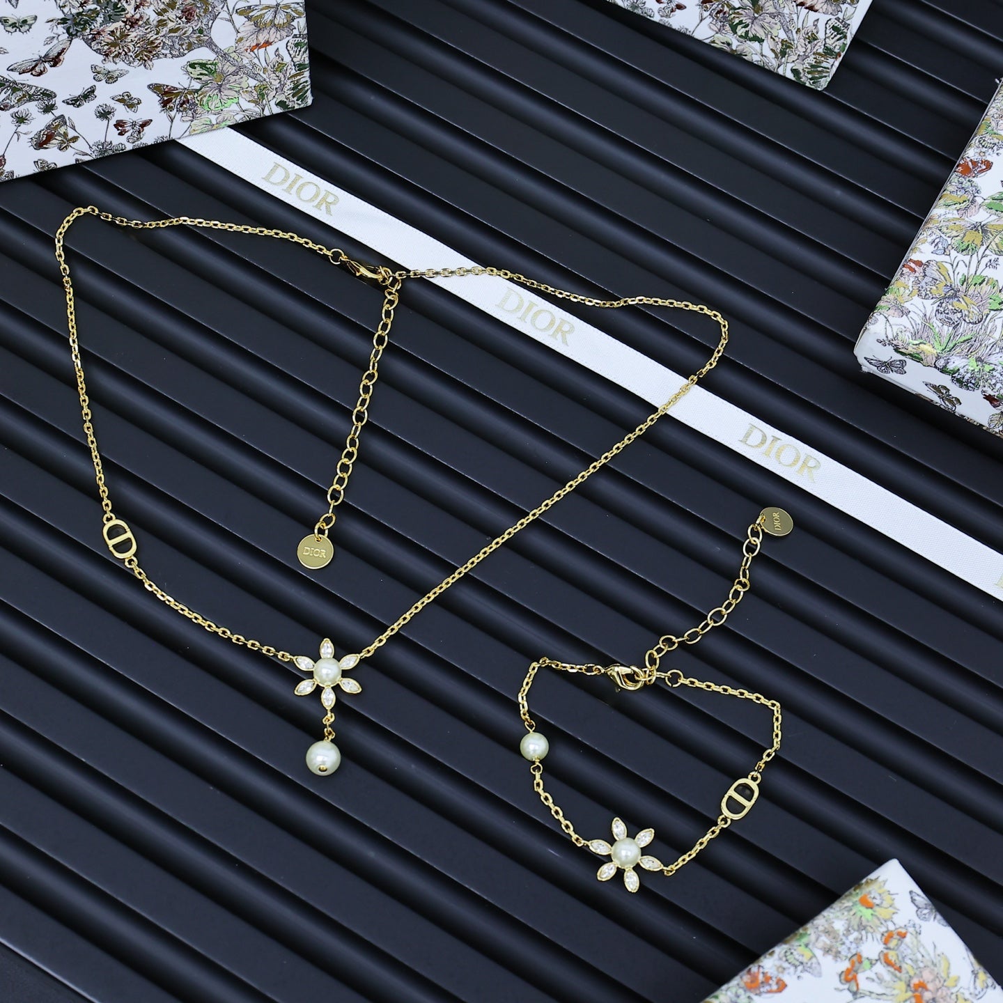 Gold-tone charm jewelry set with floral and pearl pendants, multiple linked chains.