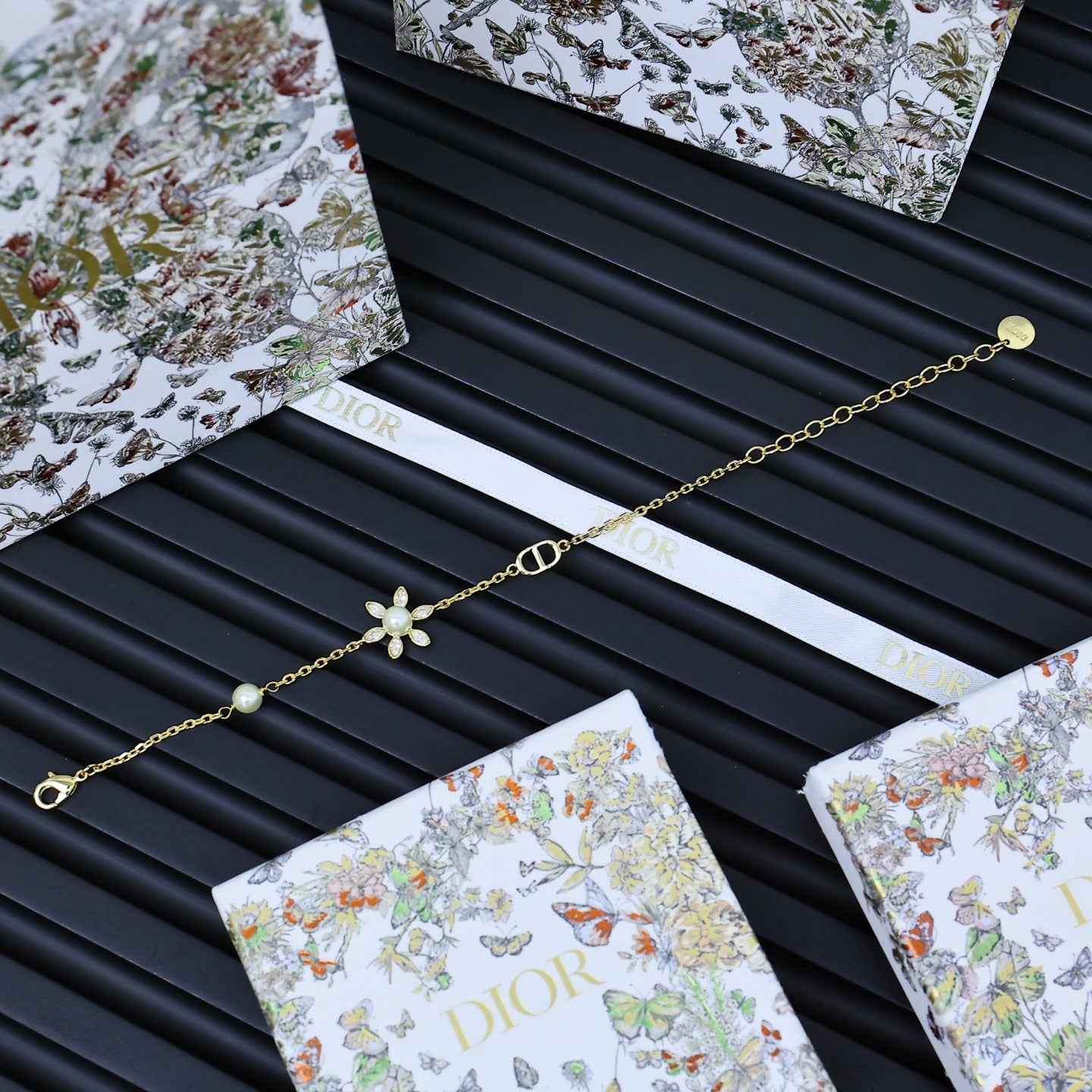 Gold-tone charm bracelet with floral pendant and pearl beads, with clasped chain.