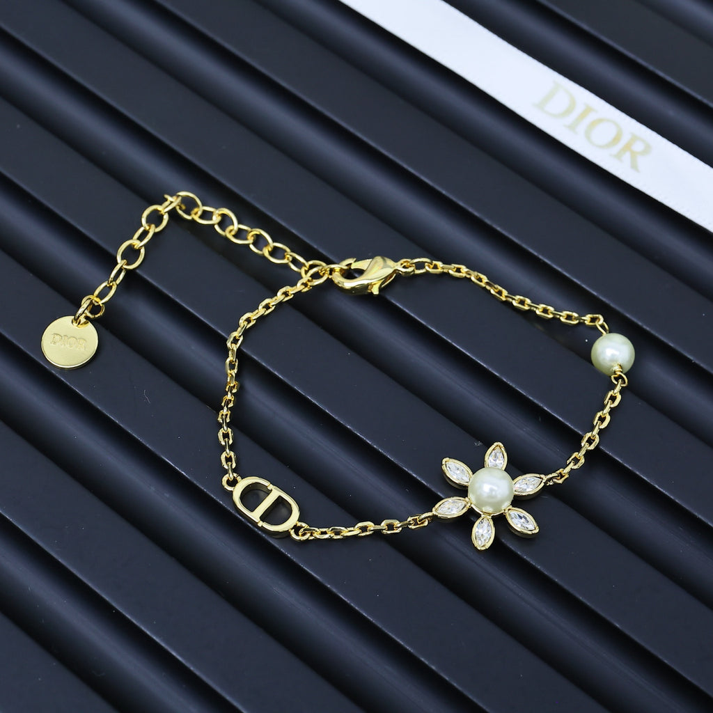 Gold-tone charm bracelet with floral pendant, small pearls, and linked chain.