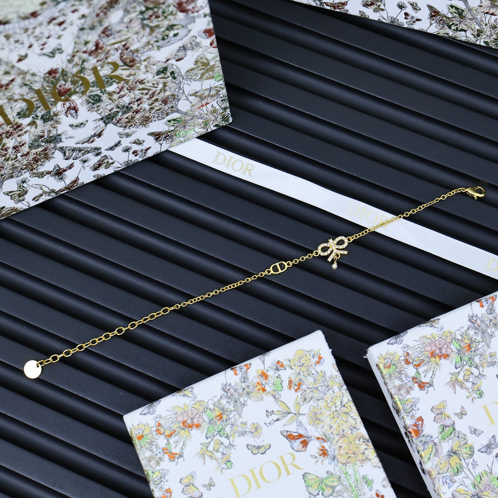 Gold-tone chain bracelet laid on Dior gift card and tissue sleeve