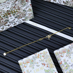 Gold-tone chain bracelet laid on Dior gift card and tissue sleeve