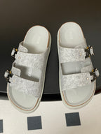 Grey Dior slide sandals with cross straps and gold buckle hardware