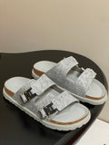Grey Dior sandals with two wide textured straps and gold-and-black buckle details