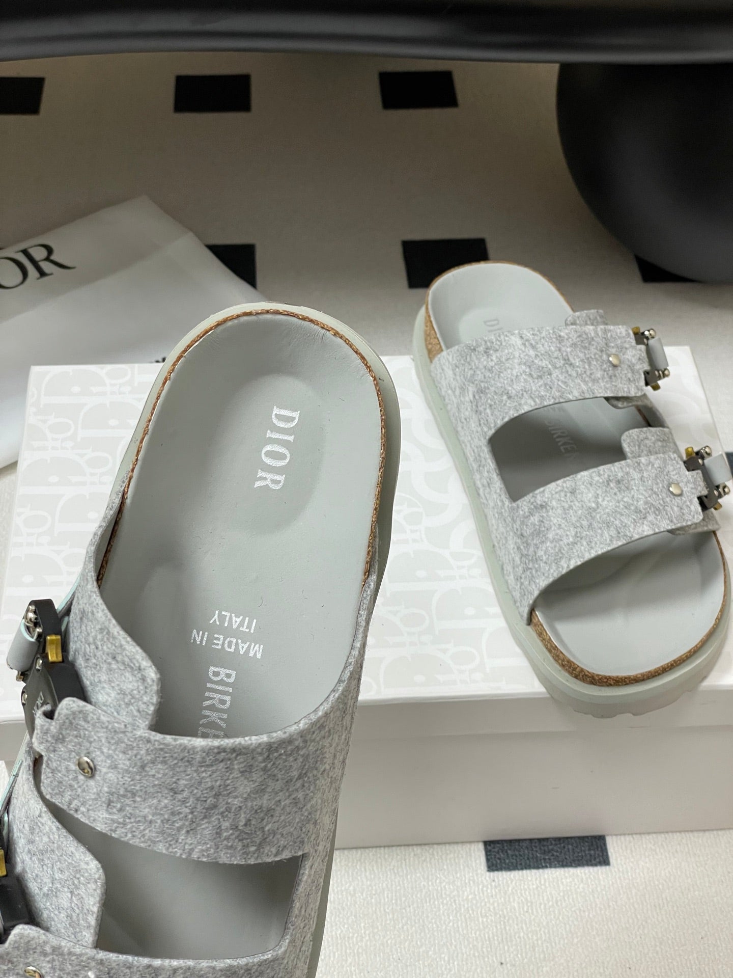 Grey Dior slide sandals with side buckle strap and textured band upper