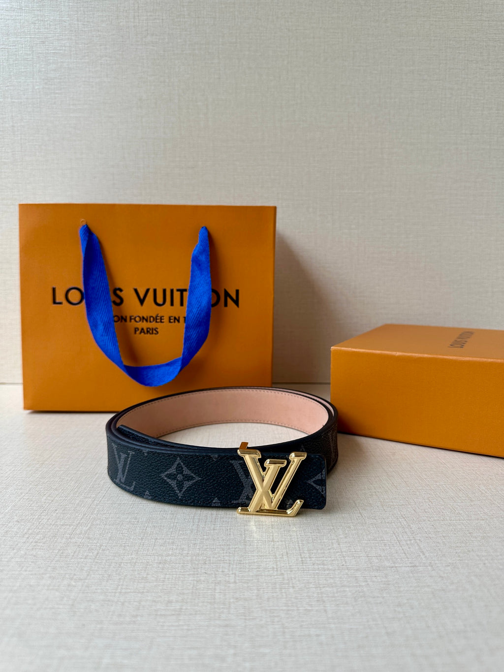 Louis Vuitton monogram belt on white cushion, silver buckle and dark strap