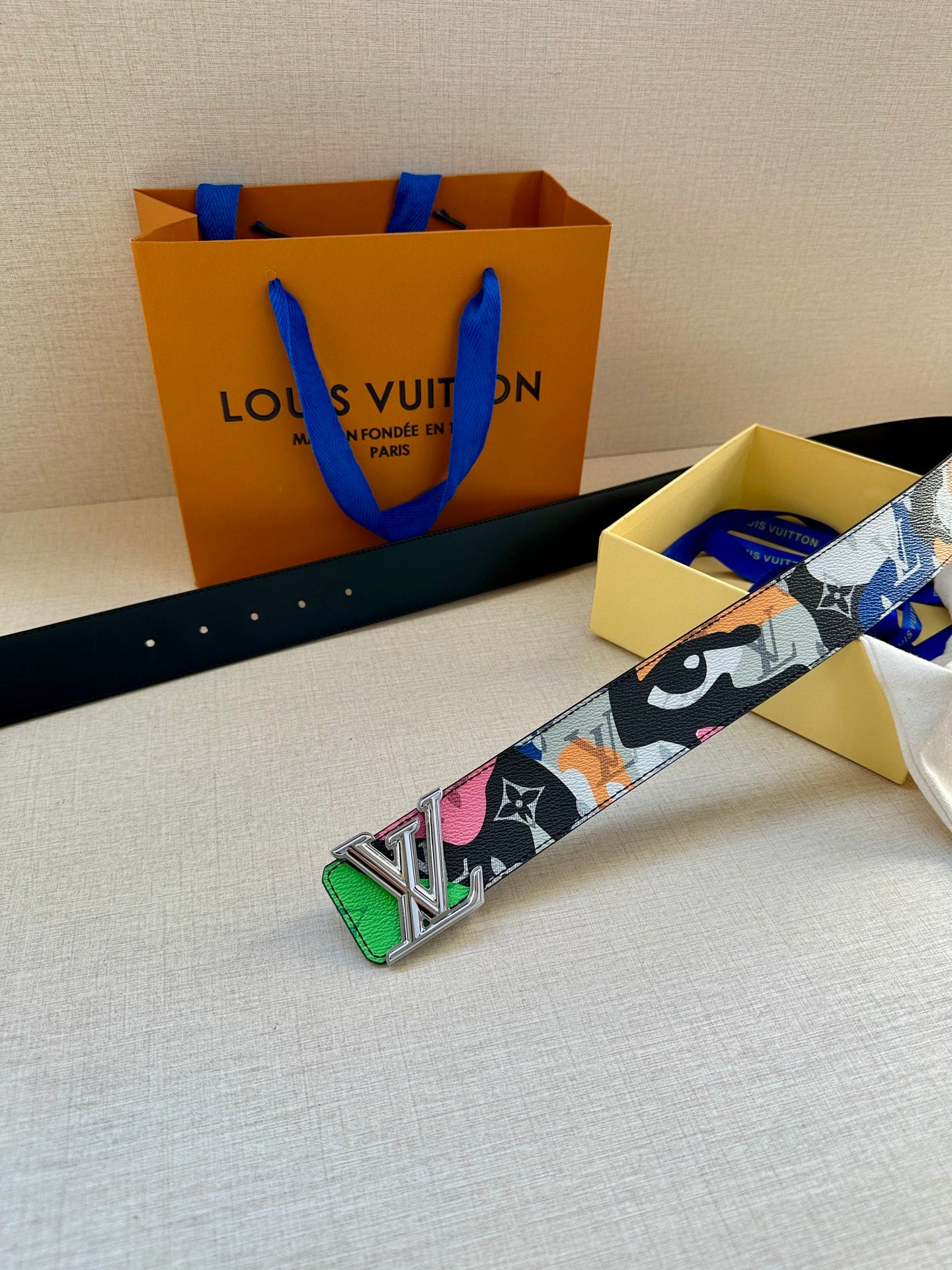 Louis Vuitton belt with multicolor printed strap and gold LV buckle centered on black edge