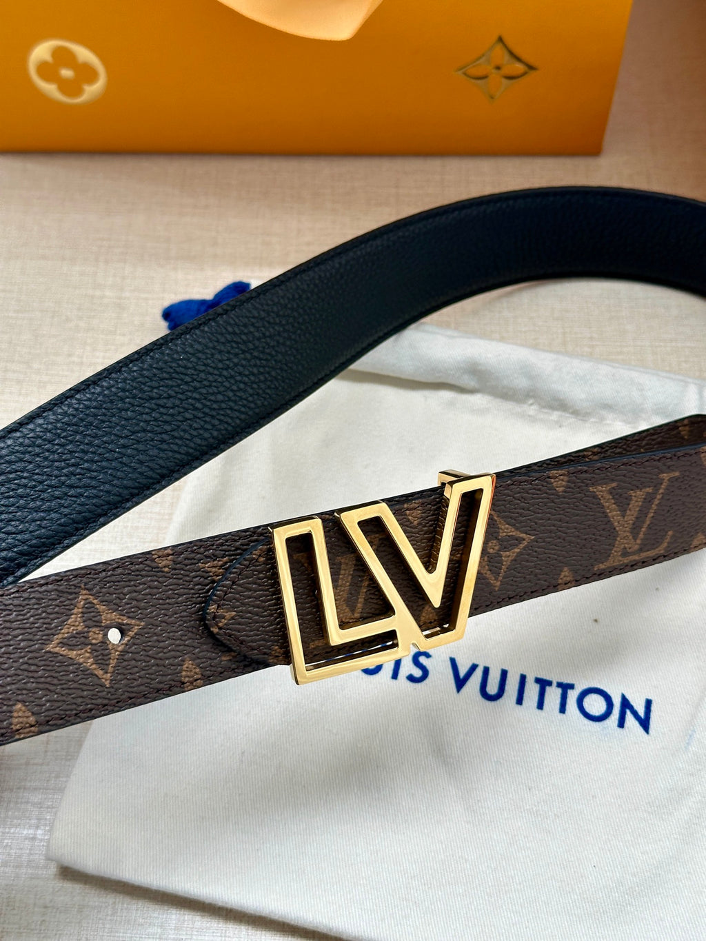 Louis Vuitton belt close-up with LV gold buckle on dark monogram strap