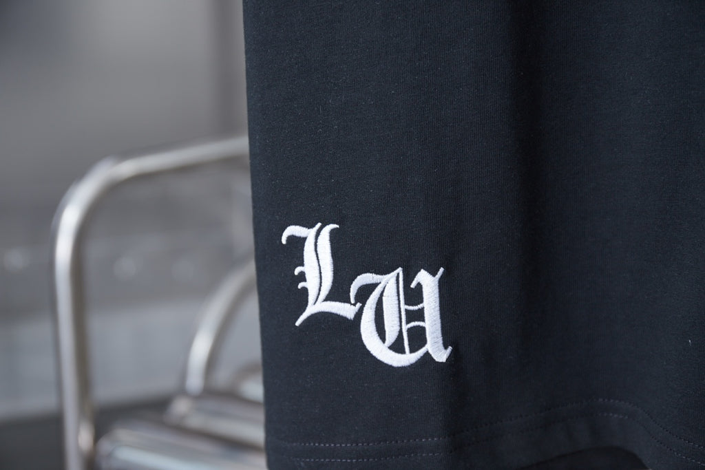 Black T-shirt with white emblem logo near the side hem