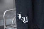 Black T-shirt with white emblem logo near the side hem